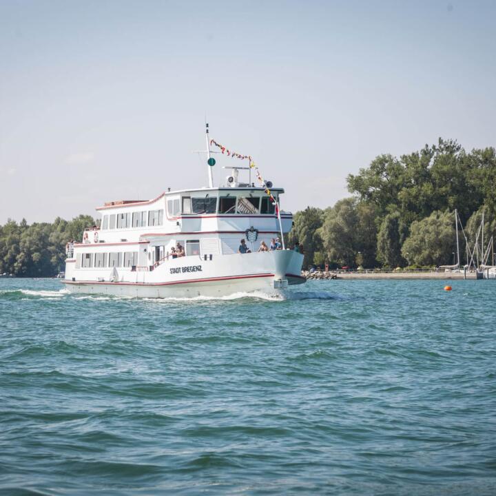 Ein Schiff der Bodenseeschiffahrt fährt im Sommer über den wunderschönen Bodensee. JUFA Hotels bietet tollen Sommerurlaub an schönen Seen für die ganze Familie.