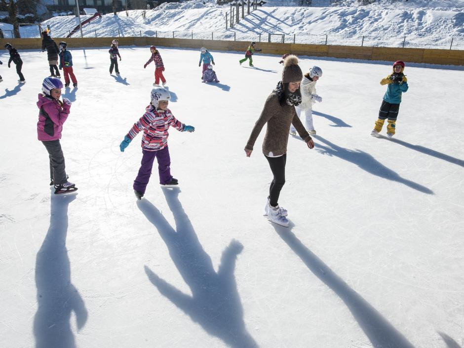 Kinder beim Eislaufen auf dem Eislaufplatz in Altenmarkt-Zauchensee. JUFA Hotels bietet erholsamen Familienurlaub und einen unvergesslichen Winterurlaub.