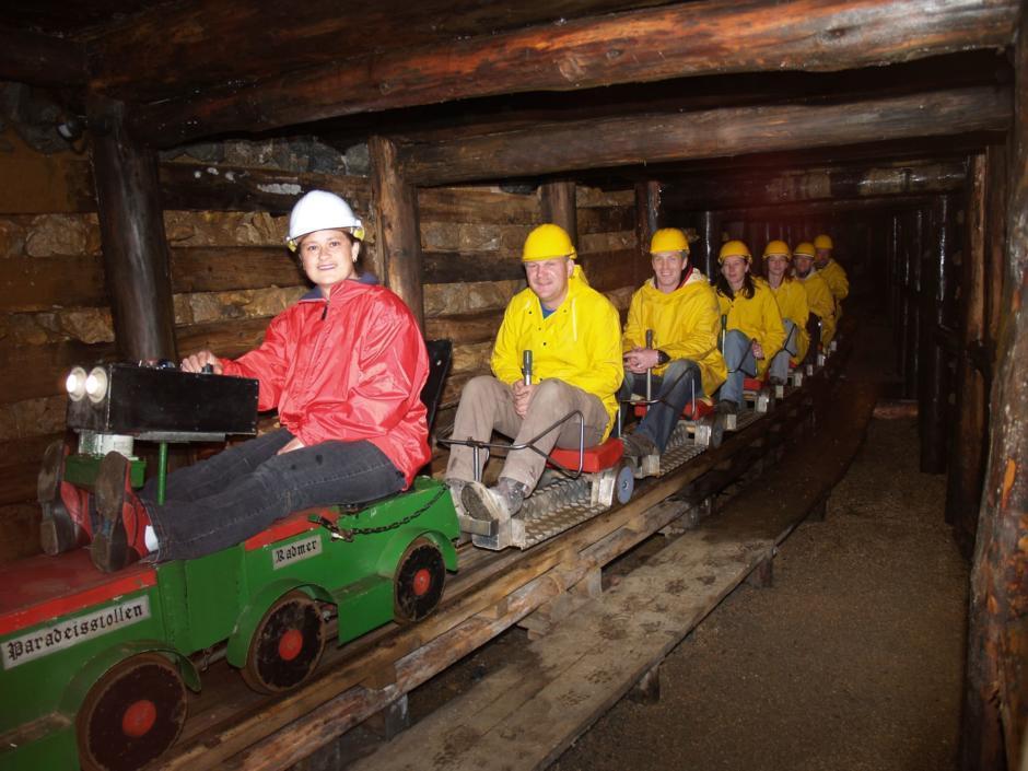 Erwachsene fahren mit der Paradeisstollen-Grubenbahn in das Kupferbergwerk Radmer. JUFA Hotels bieten erholsamen Familienurlaub und einen unvergesslichen Winter- und Wanderurlaub.