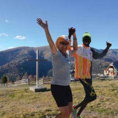 Ein Mann und eine Frau laufen händehaltend mit freudigen Gesichtern über eine Wiese mit Gipfelkreuz. JUFA Hotels bietet Ihnen den Ort für erfolgreiches Training in ungezwungener Atmosphäre für Vereine und Teams