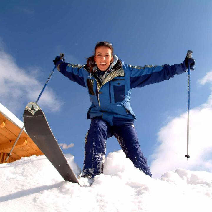 Skifahrerin im Tiefschnee im Skigebiet Präbichl bei blauem Himmel. JUFA Hotels bietet erholsamen Familienurlaub und einen unvergesslichen Winterurlaub.