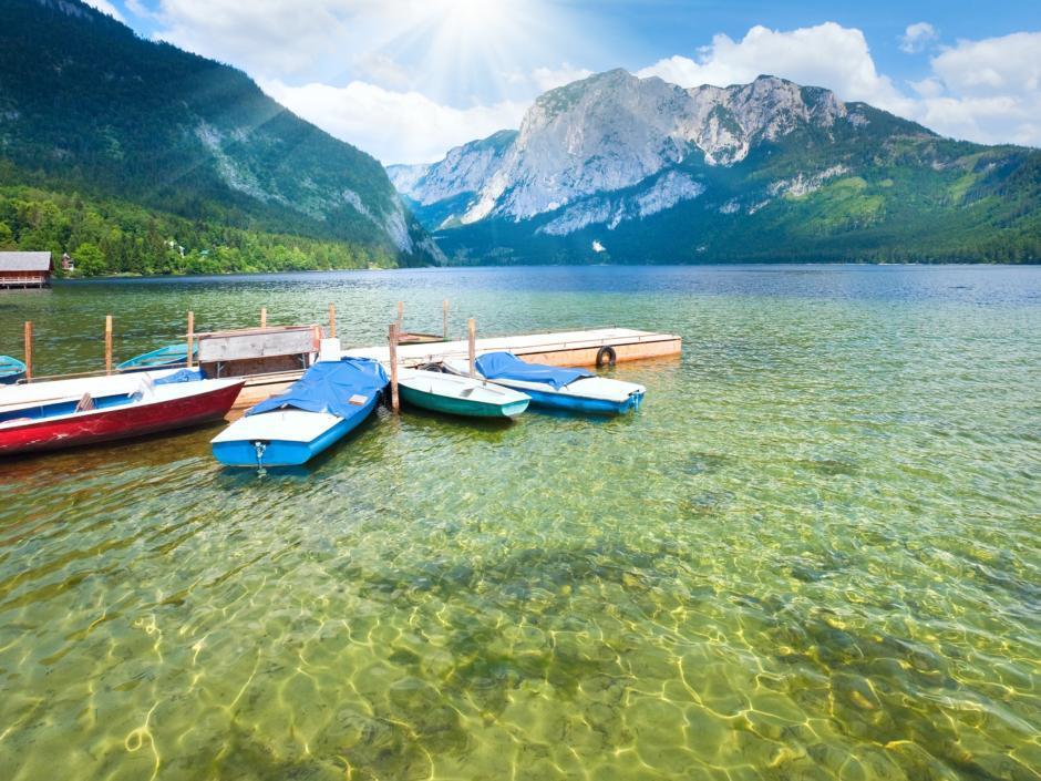 Boote liegen am Steg am Ufer des Altausseer Sees. JUFA Hotels bietet tollen Sommerurlaub an schönen Seen für die ganze Familie.