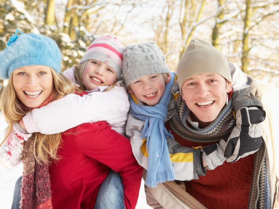 Eltern tragen ihre beiden  Kinder beim einem Winterspaziergang. JUFA Hotels bietet kinderfreundlichen und erlebnisreichen Urlaub für die ganze Familie.