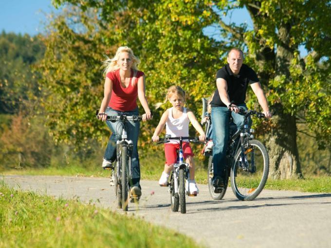 Vater, Mutter und Tochter machen eine Radtour. JUFA Hotels bietet Ihnen den Ort für erlebnisreichen Natururlaub für die ganze Familie.
