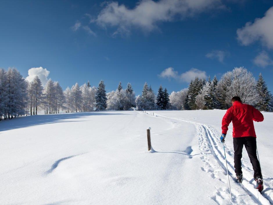 Ein Langläufer folgt einer einzelnen Spur im frischen Schnee. JUFA Hotels bietet erholsamen Familienurlaub und einen unvergesslichen Winterurlaub.