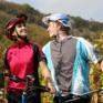 Ein Paar auf Mountainbikes macht Pause zwischen den Weinreben und umarmt sich. JUFA Hotels bietet Ihnen den Ort für erlebnisreichen Natururlaub für die ganze Familie.