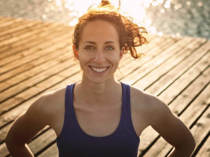 Ein Portraitfoto der JUFA Yoga Lehrerin Janina Brunner auf einem Steg am Wasser. JUFA Hotels bietet Ihnen den Ort für erfolgreiches Training in ungezwungener Atmosphäre für Vereine und Teams.