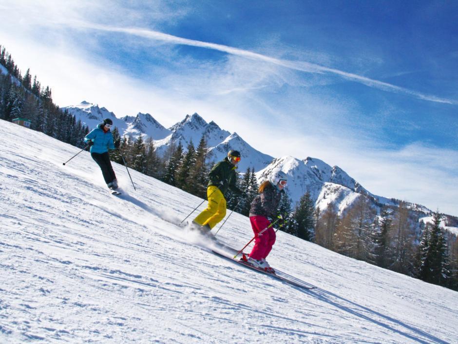 Eine Familie beim Skifahren im wunderschönen Familienskigebiet Maiskogel im Salzburger Land. JUFA Hotels bietet erholsamen Familienurlaub und einen unvergesslichen Winterurlaub.