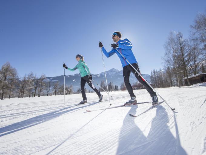 Ein Paar beim klassischen Langlaufen und Skating in Zell am See-Kaprun im Salzburger Land. JUFA Hotels bietet erholsamen Familienurlaub und einen unvergesslichen Winterurlaub.
