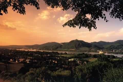Eine Panoramaaufnahme des Siebengebirges mit Rhein im Vordergrund bei Sonnenuntergang. JUFA Hotels bietet erlebnisreiche Städtetrips für die ganze Familie und den idealen Platz für Ihr Seminar.