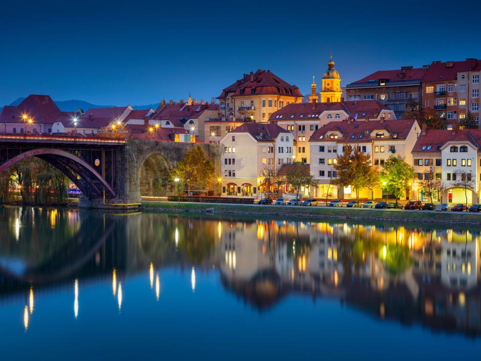 Sie sehen die Stadt Maribor im Lichterschein am Abend. Das JUFA Hotel Bad Radkersburg liegt nur 40 Kilometer von Maribor entfernt.