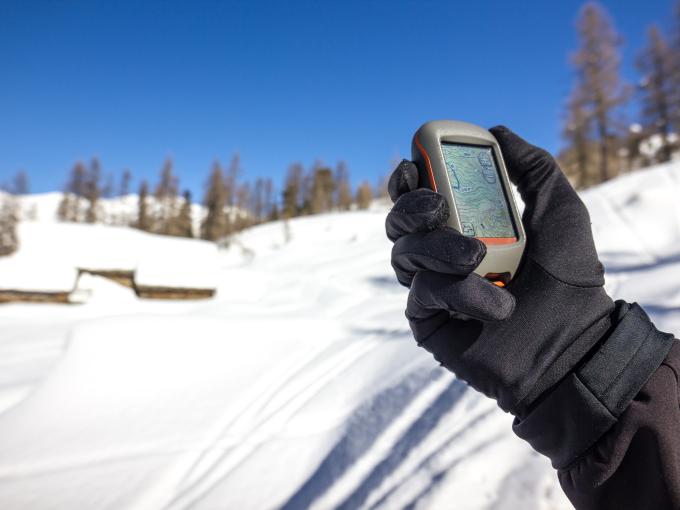 Sie sehen eine Hand mit einem GPS-Gerät im Winter.