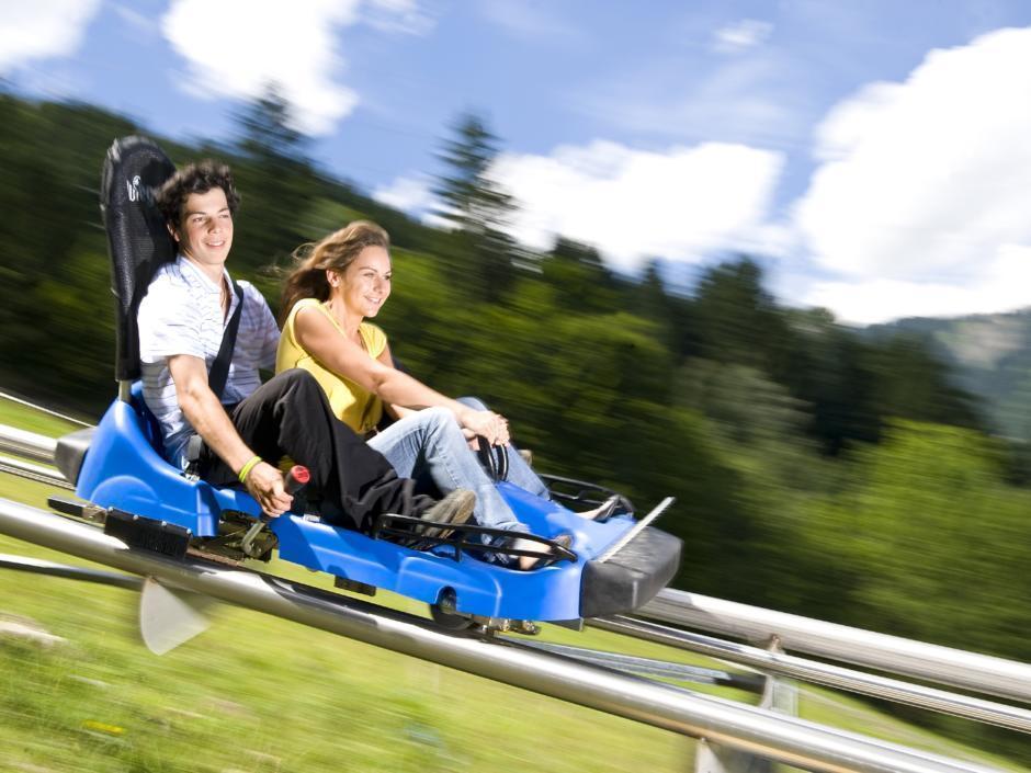 Paar beim Sommerrodeln auf dem Alpine Coaster am Golm in Montafon in Vorarlberg in der Nähe von JUFA Hotels. Der Ort für erholsamen Familienurlaub und einen unvergesslichen Winter- und Wanderurlaub.