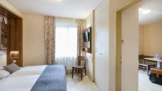 Sie sehen ein Appartement für vier Personen mit Bettdecke  im JUFA Hotel Graz City***. Der Ort für erlebnisreichen Städtetrip für die ganze Familie und der ideale Platz für Ihr Seminar.