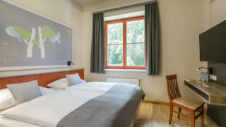 Sie sehen ein Doppelbett in einem Appartment des JUFA Hotels Sigmundsberg. Der Ort für erholsamen Familienurlaub und einen unvergesslichen Winter- und Wanderurlaub.