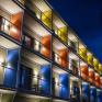Sie sehen die vollständig beleuchteten Balkone aller Zimmer mit Tische & Sessel im neuen JUFA Hotel Bad Radkersburg in der Nacht.