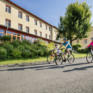 Sie sehen die Außenansicht des JUFA Hotels Waldviertel und davor eine Familie beim Rad fahren. JUFA Hotels bietet erholsamen Familienurlaub und einen unvergesslichen Winter- und Wanderurlaub.