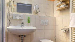 Sie sehen ein Badezimmer, das sowohl zu FF und DZ passt, im JUFA Hotel Altaussee***.