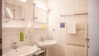 Sie sehen ein Badezimmer mit Waschbecken im JUFA Hotel Kaprun. Der Ort für erholsamen Familienurlaub und einen unvergesslichen Winter- und Wanderurlaub.