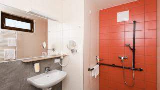 Sie sehen ein Badezimmer mit Dusche im JUFA Hotel Graz-Süd. Der Ort für erlebnisreichen Städtetrip für die ganze Familie und der ideale Platz für Ihr Seminar.