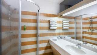 Sie sehen ein Badezimmer mit Dusche und Waschbecken im JUFA Hotel Graz City***. Der Ort für erlebnisreichen Städtetrip für die ganze Familie und der ideale Platz für Ihr Seminar.