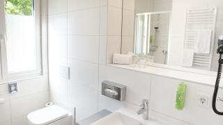 Sie sehen ein Bild vom Badezimmer in den Family & Friends-Zimmern im JUFA Hotel Garni Stubenberg in der Oststeiermark mit Dusche, WC und Waschbecken