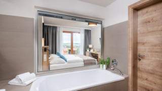 Sie sehen ein Badezimmer im JUFA Hotel Neutal – Landerlebnis mit Badewanne. JUFA Hotels bietet Ihnen den Ort für erlebnisreichen Natururlaub für die ganze Familie.
