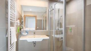 Sie sehen ein Badezimmer im JUFA Hotel Neutal – Landerlebnis mit Waschbecken. JUFA Hotels bietet Ihnen den Ort für erlebnisreichen Natururlaub für die ganze Familie.