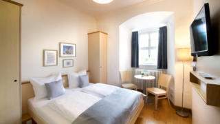 Sie sehen ein Bett im Einzel- und Doppelzimmer im JUFA Hotel Kronach – Festung Rosenberg***. Der Ort für kinderfreundlichen und erlebnisreichen Urlaub für die ganze Familie.