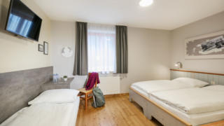 Sie sehen ein Dreibettzimmer im JUFA Hotel Eisenerz. Der Ort für erholsamen Familienurlaub und einen unvergesslichen Winter- und Wanderurlaub.