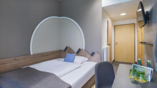 Sie sehen ein Bett im Einzelzimmer Plus im JUFA Hotel Wipptal. Der Ort für erholsamen Familienurlaub und einen unvergesslichen Winter- und Wanderurlaub.