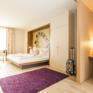 Bett in der Suite large mit Schreibtisch im JUFA Hotel Wien City. Der Ort für erlebnisreichen Städtetrip für die ganze Familie und der ideale Platz für Ihr Seminar.