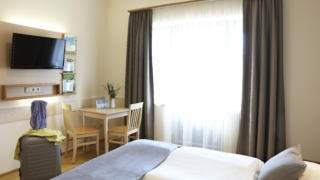 Sie sehen ein Bett in einem Doppelzimmer im JUFA Hotel Pöllau - Bio-Landerlebnis. Der Ort für erholsamen Familienurlaub und einen unvergesslichen Winter- und Wanderurlaub.