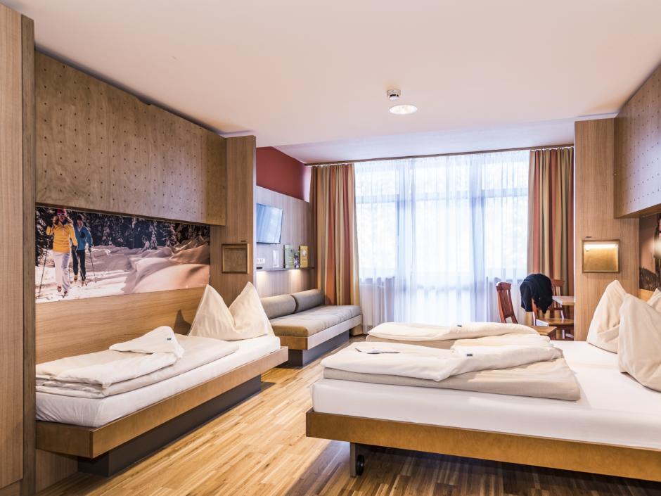 Sie sehen Betten im Familienzimmer large im JUFA Hotel Altenmarkt. Der Ort für erholsamen Familienurlaub und einen unvergesslichen Winterurlaub.