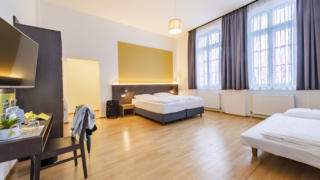 Sie sehen Betten in einem Familienzimmer Typ Family & Friends 3 im JUFA Hotel Bregenz mit einem Tisch. JUFA Hotels bietet erlebnisreichen Städtetrip für die ganze Familie und den idealen Platz für Ihr Seminar.