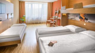 Sie sehen ein Vierbettzimmer mit einem Doppelbett, einem Einzelbett und einem Stockbett im JUFA Hotel Altenmarkt***.