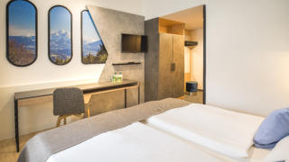 Sie sehen Betten im Doppelzimmer Plus im JUFA Hotel Wipptal. Der Ort für erholsamen Familienurlaub und einen unvergesslichen Winter- und Wanderurlaub.