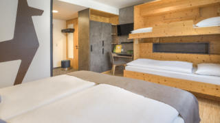 Sie sehen Betten im Familienzimmer FF4 im JUFA Hotel Wipptal. Der Ort für erholsamen Familienurlaub und einen unvergesslichen Winter- und Wanderurlaub.