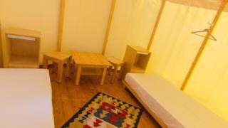 Sie sehen zwei Betten im Jurtenzelt im JUFA Hotel Neutal – Landerlebnis mit einem Teppich. JUFA Hotels bietet kinderfreundlichen und erlebnisreichen Urlaub für die ganze Familie.