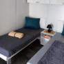 Sie sehen zwei Betten in einem Mobile Home beim JUFA Vulkan Thermen-Resort mit einem Nachtkästchen. JUFA Hotels bietet erholsamen Thermenspass für die ganze Familie.