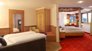 Sie sehen Betten in einer Suite Typ 4 im JUFA Alpenhotel Saalbach**** mit Sitzecke. JUFA Hotels bietet erholsamen Familienurlaub und einen unvergesslichen Winterurlaub.