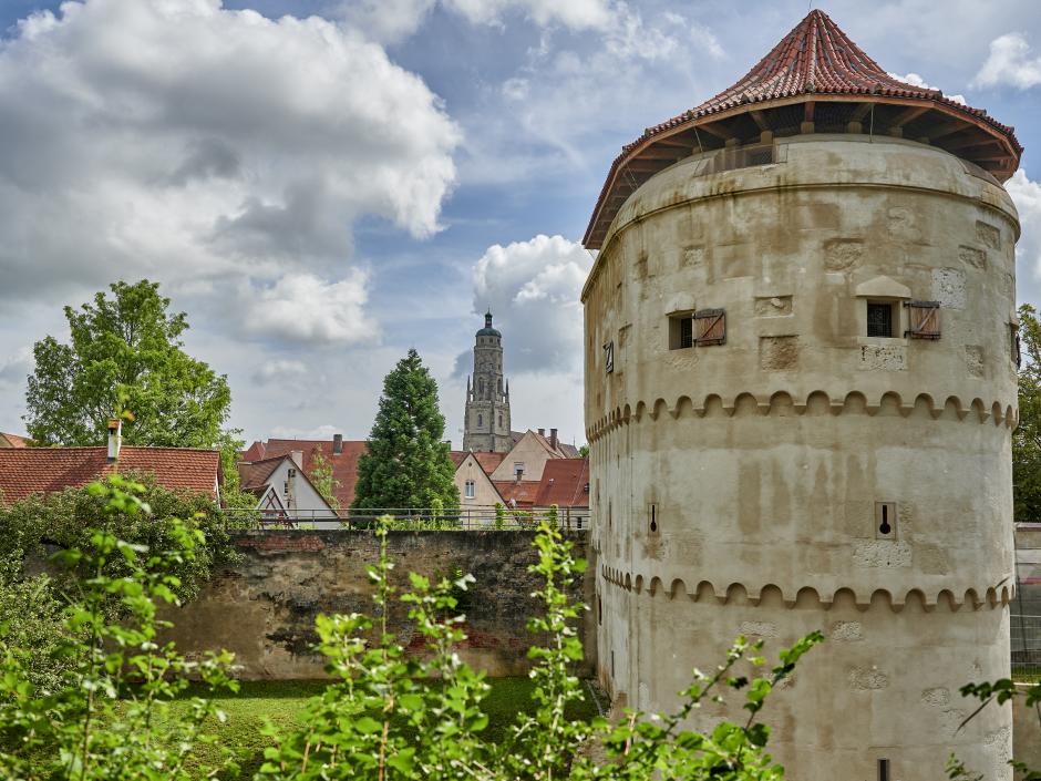 Sie sehen den Kirchturm Daniel in Nördlingen mit der Stadtmauer.