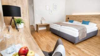 Sie sehen ein Doppelbett in einem Doppelzimmer Plus im JUFA Hotel Neutal – Landerlebnis mit frischen Äpfeln. JUFA Hotels bietet Ihnen den Ort für erlebnisreichen Natururlaub für die ganze Familie.