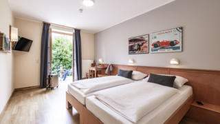 Sie sehen ein Doppelbett in einem Doppelzimmer im JUFA Hotel Seckau mit Terrasse. JUFA Hotels bietet erholsamen Familienurlaub und einen unvergesslichen Winter- und Wanderurlaub.
