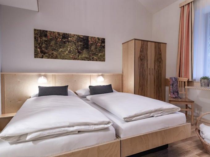 Sie sehen ein Doppelbett in einem Doppelzimmer im JUFA Natur-Hotel Bruck mit Wandbild. JUFA Hotels bietet Ihnen den Ort für erlebnisreichen Natururlaub für die ganze Familie.