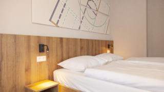 Sie sehen ein Doppelbett im Familienzimmer FF3 im JUFA Hotel Mariazell – Erlaufsee Sport-Resort. Der Ort für erfolgreiches Training in ungezwungener Atmosphäre für Vereine und Teams.