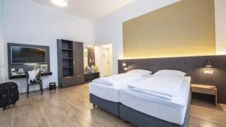 Sie sehen ein Doppelbett in einem Familienzimmer Typ Family & Friends 3 im JUFA Hotel Bregenz mit TV. JUFA Hotels bietet erlebnisreichen Städtetrip für die ganze Familie und den idealen Platz für Ihr Seminar.