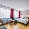 Sie sehen ein Doppelbett in einem Familienzimmer Typ Family and Friends 3 im JUFA Hotel Königswinter/Bonn mit Tisch. JUFA Hotels bietet erlebnisreichen Städtetrip für die ganze Familie und den idealen Platz für Ihr Seminar.