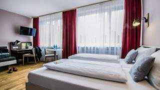 Sie sehen ein Doppelbett in einem Familienzimmer Typ Family and Friends 3 im JUFA Hotel Königswinter/Bonn mit TV. JUFA Hotels bietet erlebnisreichen Städtetrip für die ganze Familie und den idealen Platz für Ihr Seminar.