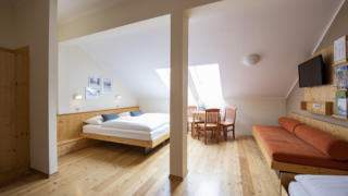 Sie sehen ein Doppelbett in einem Familienzimmer Typ Family and Friends 4 im JUFA Hotel Murau mit TV. JUFA Hotels bietet erholsamen Familienurlaub und einen unvergesslichen Winter- und Wanderurlaub.
